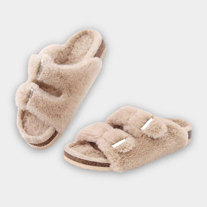 Pair of beige fuzzy slippers on a light gray background